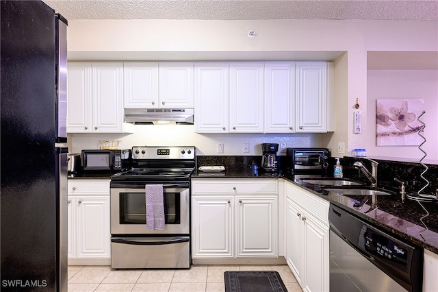 kitchen featuring stainless steel appliances, white cabinetry, dark stone countertops, and sink