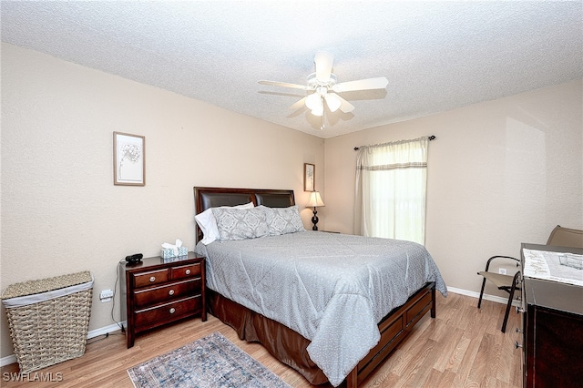 bedroom with a textured ceiling, light hardwood / wood-style floors, and ceiling fan