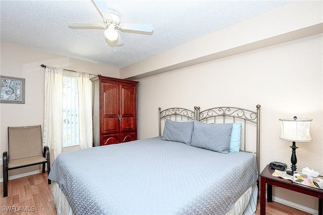 bedroom featuring ceiling fan, light wood-type flooring, a textured ceiling, and multiple windows