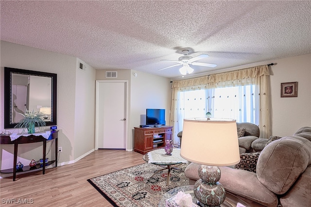 living room featuring a textured ceiling, light hardwood / wood-style flooring, and ceiling fan