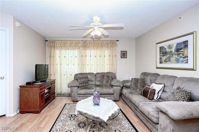 living room with a textured ceiling, light hardwood / wood-style floors, and ceiling fan