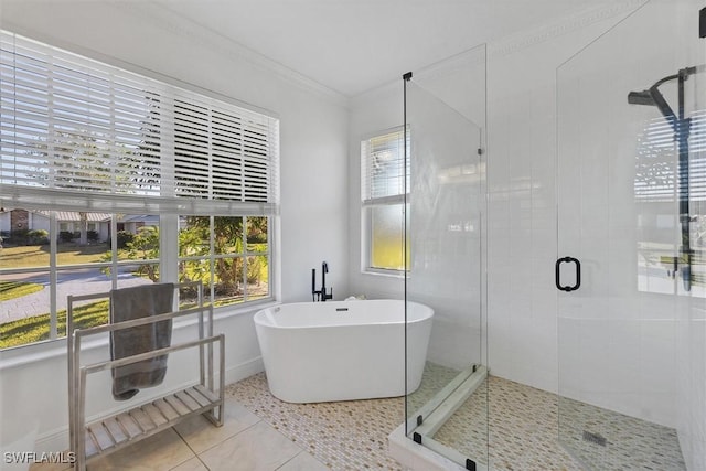 full bathroom featuring a soaking tub, ornamental molding, a stall shower, tile patterned flooring, and baseboards