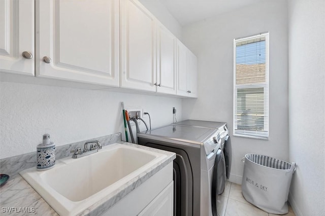 clothes washing area with washer and dryer, cabinets, light tile patterned floors, and sink