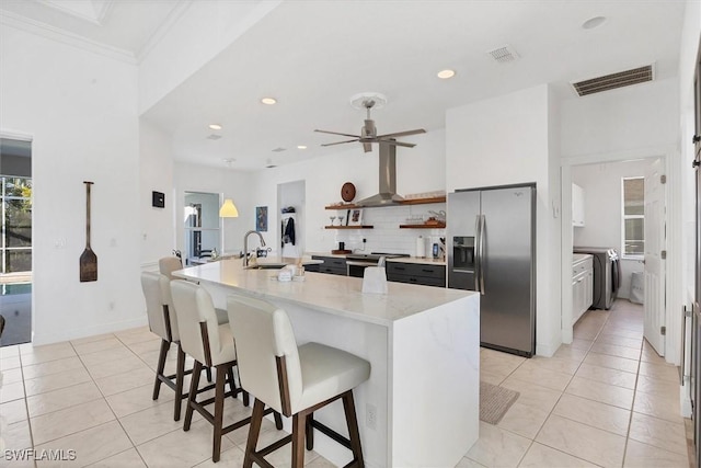 kitchen with sink, a center island with sink, appliances with stainless steel finishes, and a kitchen breakfast bar