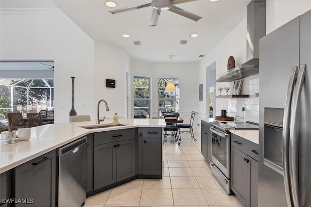 kitchen featuring appliances with stainless steel finishes, wall chimney range hood, sink, light tile patterned floors, and gray cabinetry