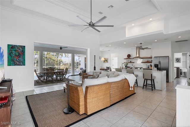 living room featuring a high ceiling, a raised ceiling, crown molding, and light tile patterned flooring