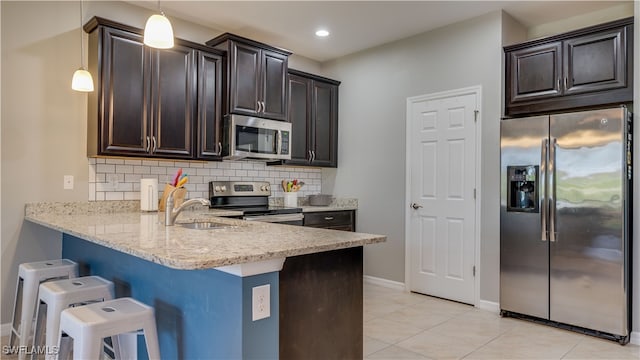 kitchen with a kitchen breakfast bar, tasteful backsplash, decorative light fixtures, light tile patterned flooring, and stainless steel appliances