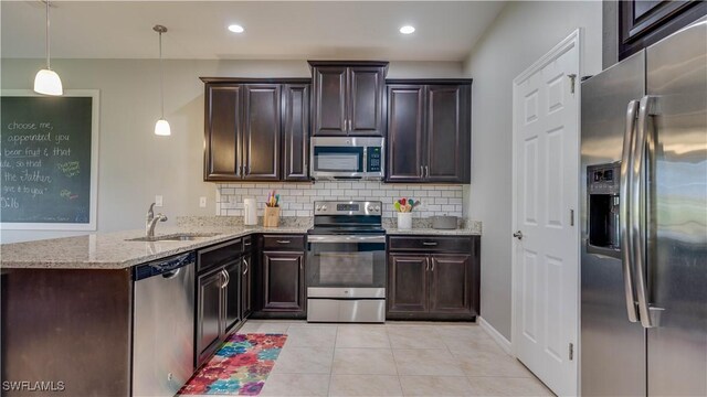 kitchen featuring kitchen peninsula, backsplash, stainless steel appliances, sink, and hanging light fixtures