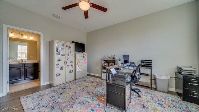 home office featuring light wood-type flooring, ceiling fan, and sink