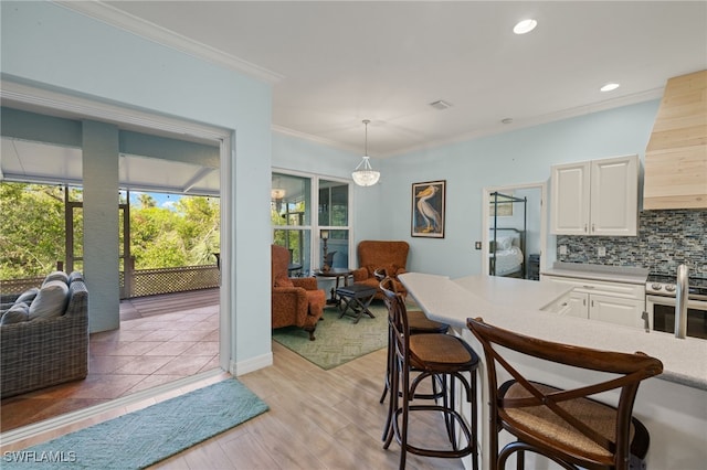 kitchen featuring backsplash, pendant lighting, light hardwood / wood-style floors, white cabinets, and ornamental molding