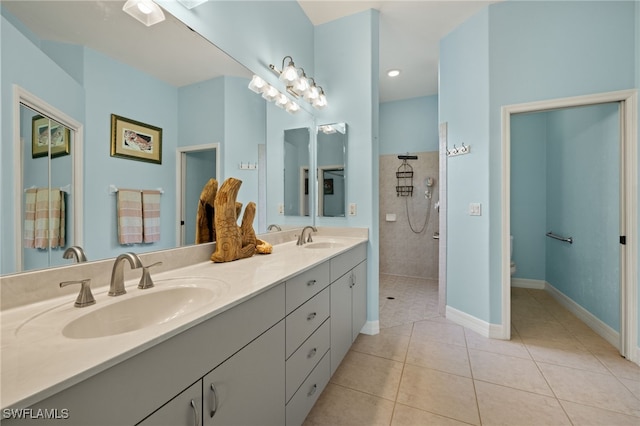 bathroom with tile patterned flooring, vanity, tiled shower, and toilet