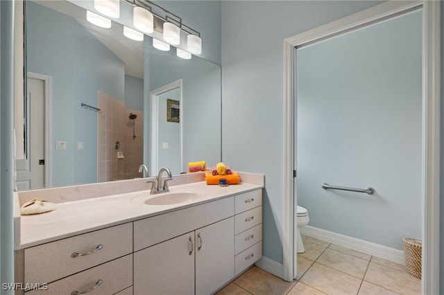 bathroom with tiled shower, tile patterned floors, vanity, and toilet