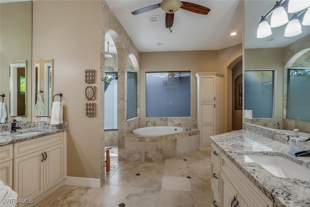 bathroom with ceiling fan, a healthy amount of sunlight, tiled tub, and vanity