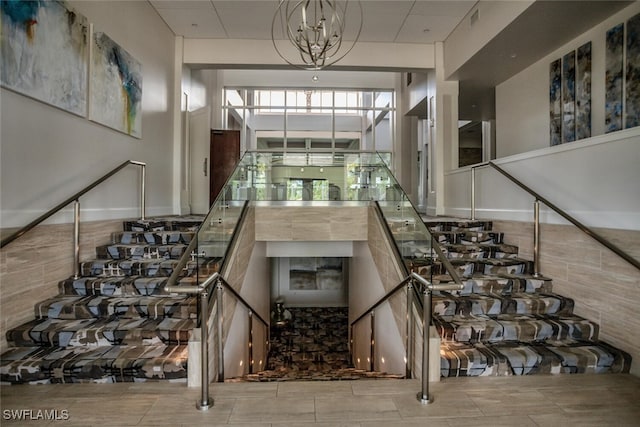 staircase with tile patterned floors and a notable chandelier