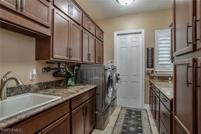 washroom featuring washing machine and dryer, sink, light tile patterned floors, and cabinets