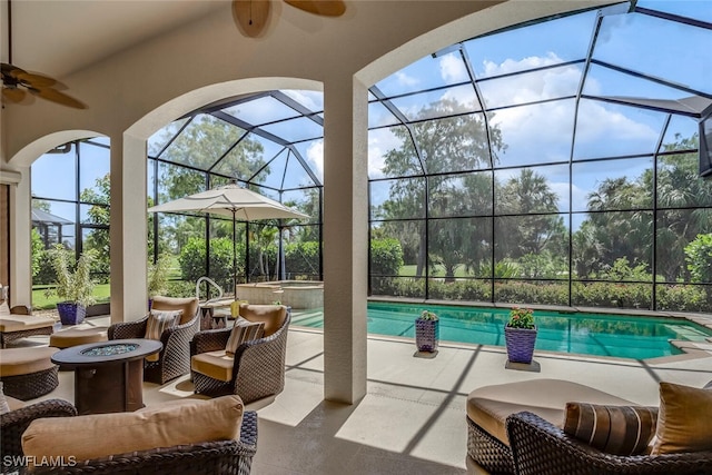 view of swimming pool featuring ceiling fan, glass enclosure, an in ground hot tub, and an outdoor fire pit