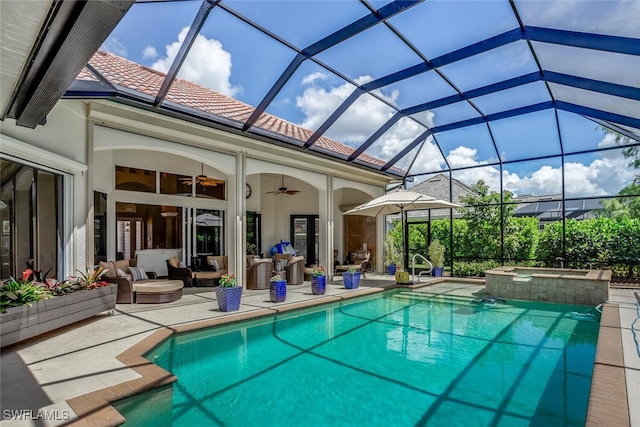 view of pool with glass enclosure, ceiling fan, outdoor lounge area, a patio area, and an in ground hot tub