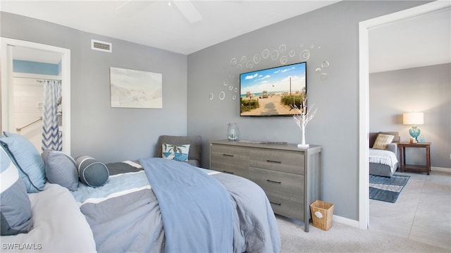 bedroom featuring ceiling fan, light colored carpet, and connected bathroom