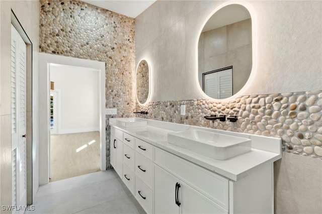 bathroom with vanity, concrete flooring, and tile walls