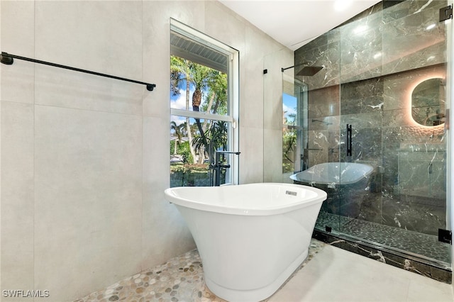 bathroom featuring plus walk in shower and tile walls