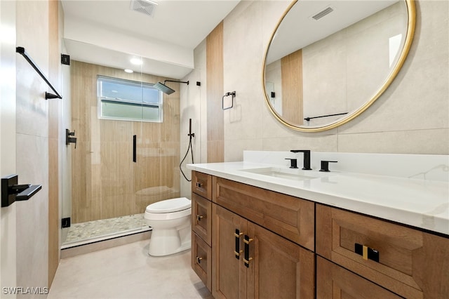 bathroom with an enclosed shower, vanity, toilet, and tile walls