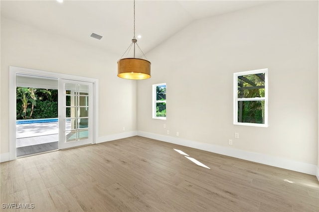 unfurnished room featuring french doors, hardwood / wood-style flooring, and high vaulted ceiling