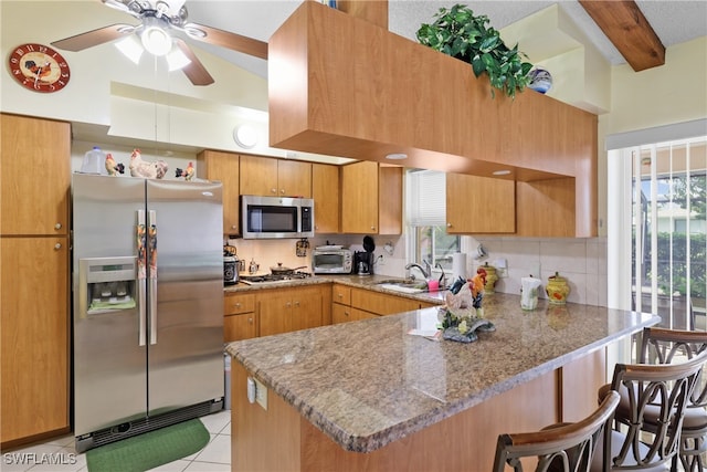 kitchen featuring stainless steel appliances, tasteful backsplash, beamed ceiling, kitchen peninsula, and a breakfast bar