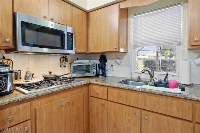 kitchen with decorative backsplash, sink, stainless steel appliances, and light stone counters