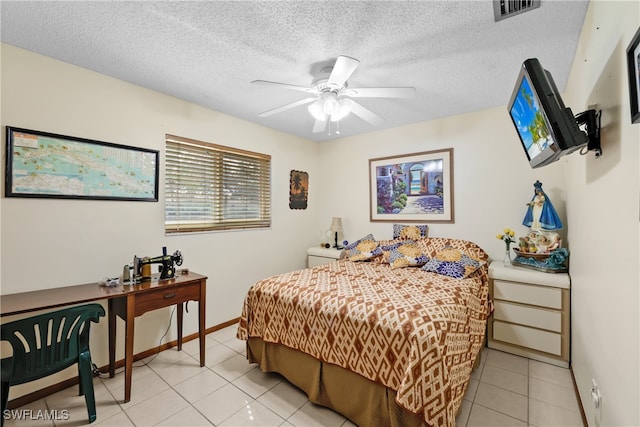 bedroom with ceiling fan, light tile patterned floors, and a textured ceiling