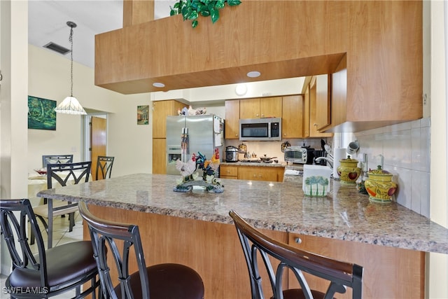 kitchen with a breakfast bar, stone countertops, kitchen peninsula, and appliances with stainless steel finishes