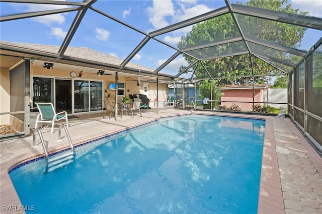 view of swimming pool with glass enclosure, ceiling fan, and a patio area