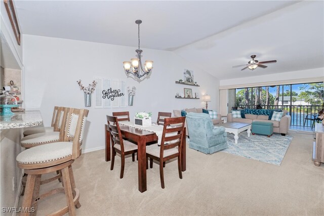 dining area with ceiling fan with notable chandelier, light colored carpet, and lofted ceiling