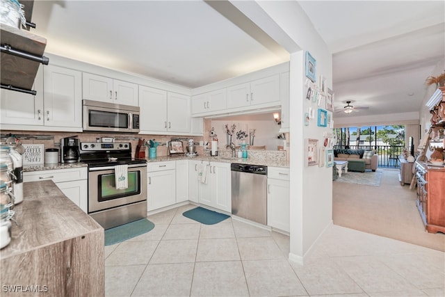 kitchen with light tile patterned floors, stainless steel appliances, and white cabinets