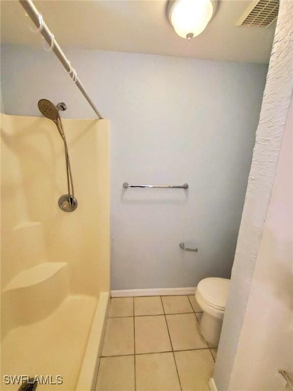 bathroom featuring tile patterned flooring, toilet, and a shower