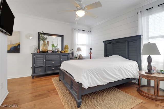 bedroom featuring wooden walls, light hardwood / wood-style flooring, ceiling fan, and ornamental molding