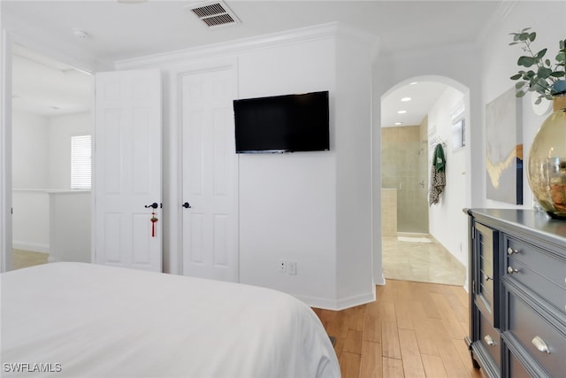 bedroom with crown molding, ensuite bathroom, and light wood-type flooring