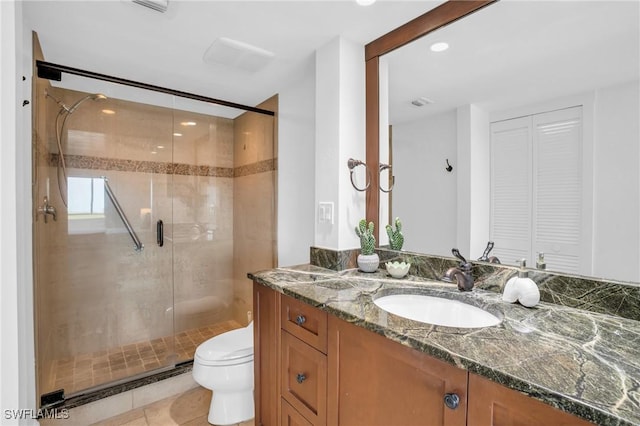 bathroom featuring a closet, a stall shower, vanity, toilet, and tile patterned flooring