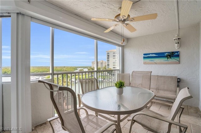 sunroom / solarium with ceiling fan and a water view