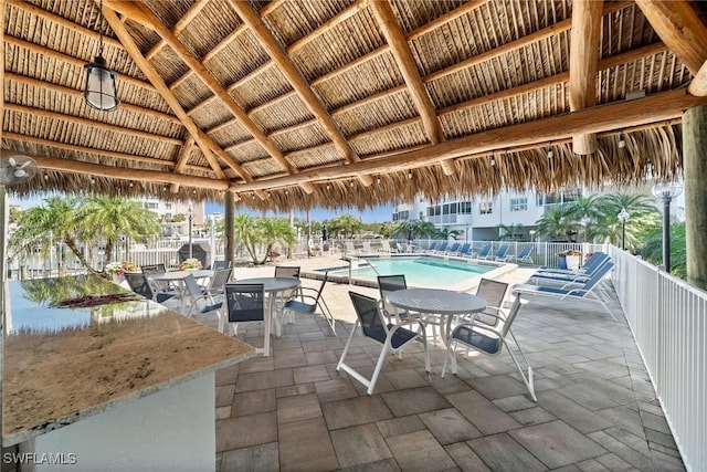 view of patio / terrace featuring a gazebo, outdoor dining area, a community pool, and fence
