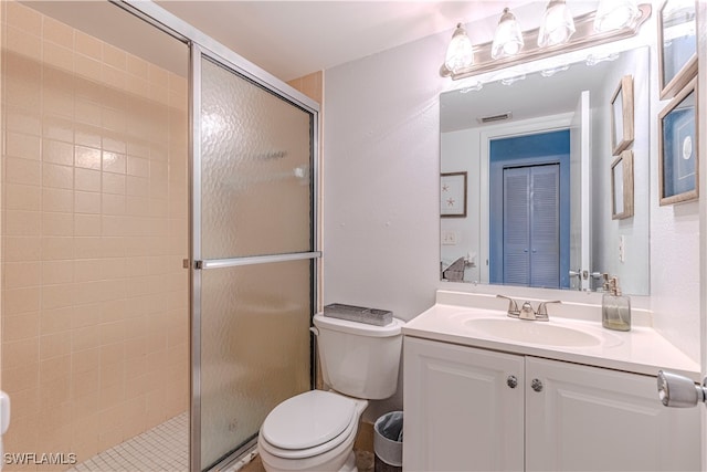 bathroom featuring vanity, toilet, and a shower with shower door