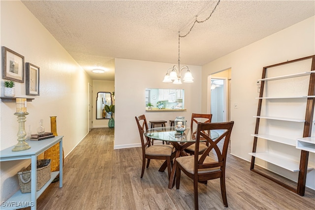 dining room featuring hardwood / wood-style floors, a textured ceiling, and a notable chandelier