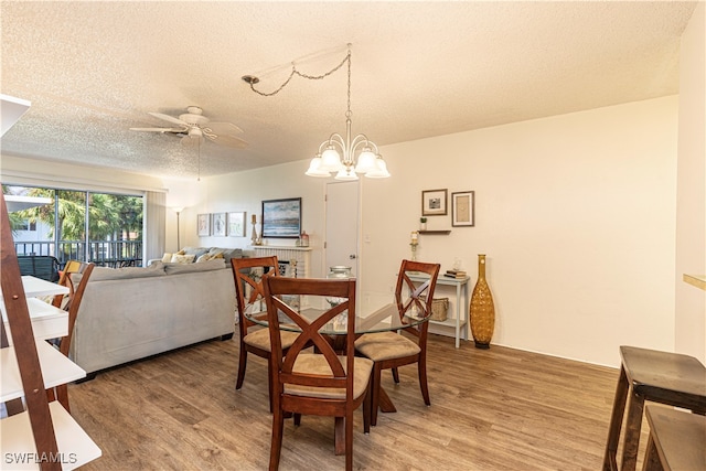 dining area featuring ceiling fan with notable chandelier, wood-type flooring, and a textured ceiling