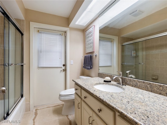 full bathroom with tile patterned flooring, vanity, enclosed tub / shower combo, and toilet