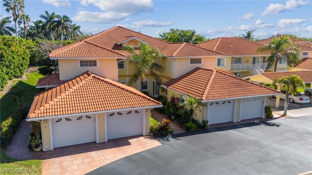 mediterranean / spanish-style home with a garage, a tiled roof, and stucco siding