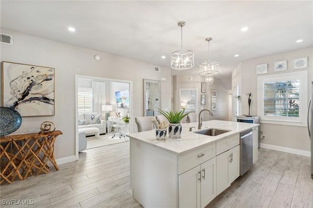 kitchen with hanging light fixtures, stainless steel dishwasher, white cabinets, a sink, and an island with sink