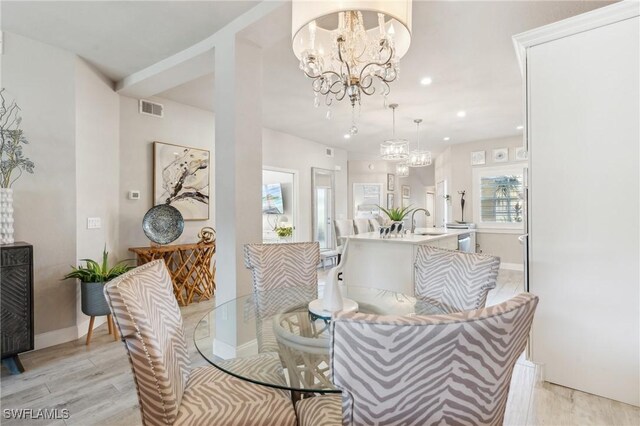 dining area featuring a notable chandelier, light hardwood / wood-style floors, and sink