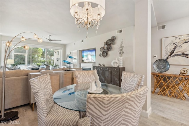 dining room featuring light hardwood / wood-style flooring and ceiling fan with notable chandelier