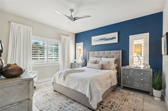 bedroom featuring light wood finished floors, a ceiling fan, and baseboards