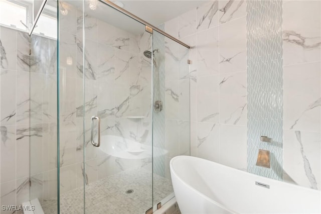 bathroom with a freestanding bath, tile walls, and a marble finish shower