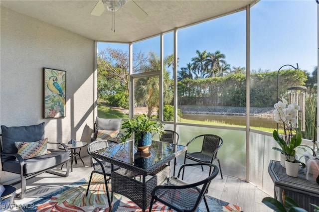 sunroom / solarium featuring a wealth of natural light, ceiling fan, and a water view